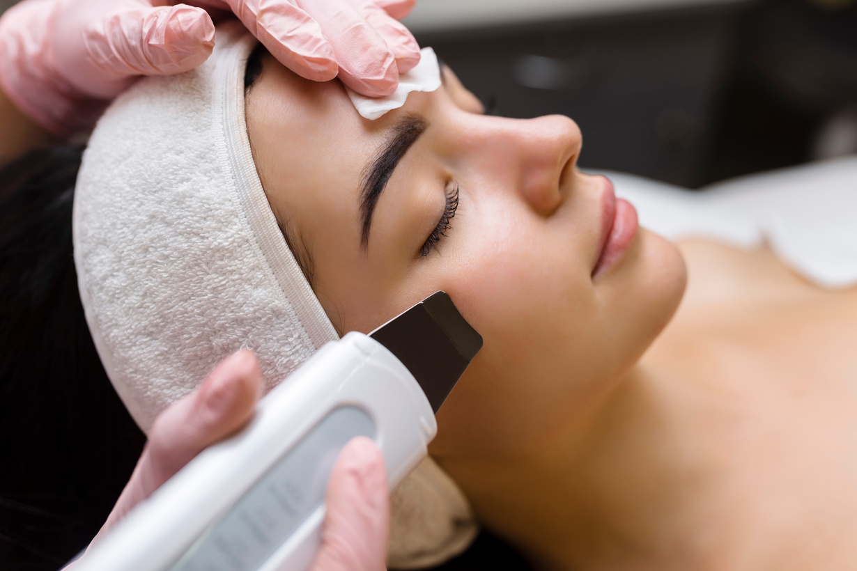 Facial cleansing with ultrasound scrubber. Woman receiving ultrasound facial peeling and cleansing. Cosmetology and face skin care. Facial treatment